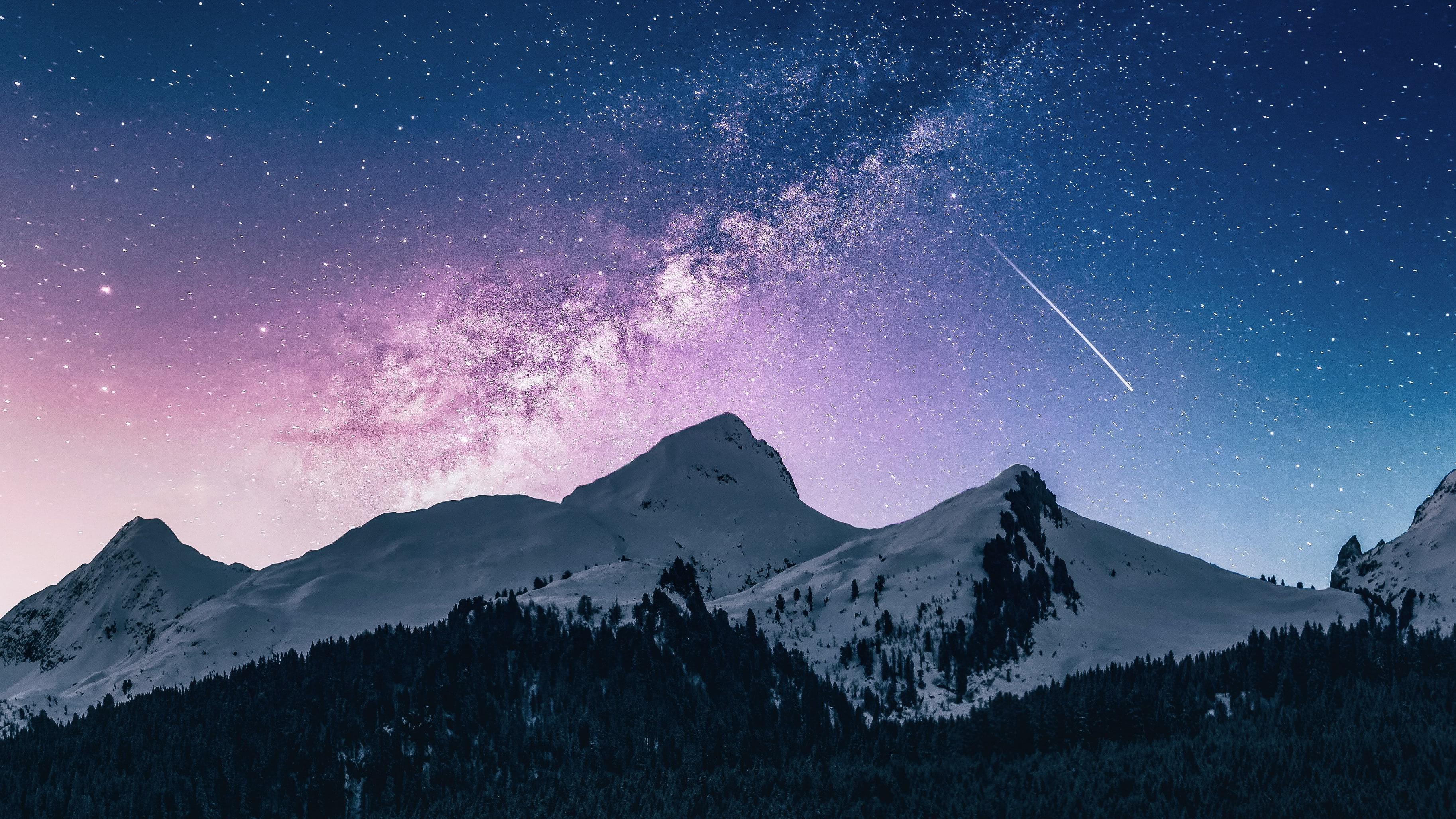 Photo of a shooting star in the night sky over a mountain ridge in Moena, Italy